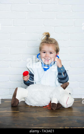 Happy baby veterinario esamina toy animale con uno stetoscopio Foto Stock