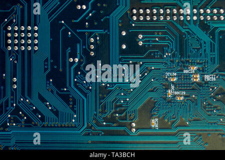 Lato posteriore di colore blu per scheda a circuito stampato il circuito vicino la tecnologia lo sfondo con il fuoco selettivo e alcune polveri su di esso Foto Stock