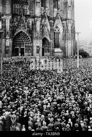 Una folla è in ascolto di una banda di ottoni con un coro sulla Domplatte davanti alla Cattedrale di Colonia, come parte delle manifestazioni di protesta contro il Trattato di Versailles. In background, portali di ingresso della cattedrale. Foto Stock