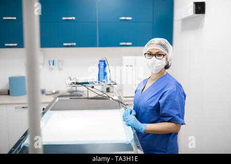 Vet indossando uniforme blu e una maschera per la preparazione per la chirurgia Foto Stock