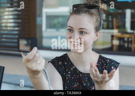 Un caucasian giovane ragazza facendo un video blog (vlog) o una foto tenendo la fotocamera di piccole dimensioni Foto Stock