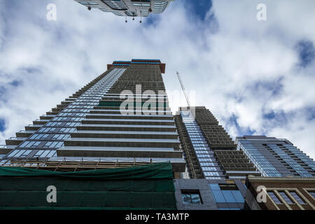 La gru e la costruzione di dispositivo su un sito di costruzione di un grattacielo nel centro cittadino di Toronto, circondato da altre alte torri e condomini nonché olde Foto Stock