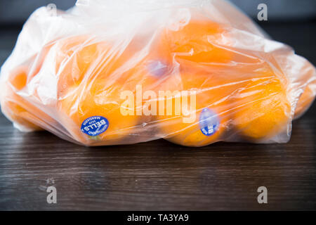 Mandarini acquistati al supermercato in un singolo uso di produrre una busta di plastica. Non rispettosi dell'ambiente. Bella la frutta di arancia, di marca con adesivo. Foto Stock