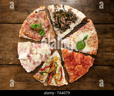 Varietà di fette di pizza sul tavolo di legno Foto Stock