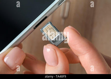 Donna di inserire la scheda SIM nel telefono cellulare, primo piano Foto Stock