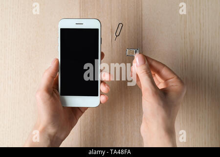 Donna di inserire la scheda SIM nel telefono cellulare, vista dall'alto Foto Stock