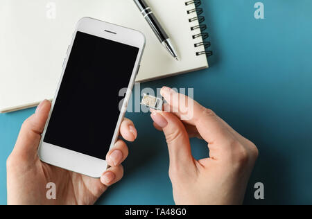 Donna di inserire la scheda SIM nel telefono cellulare, primo piano Foto Stock