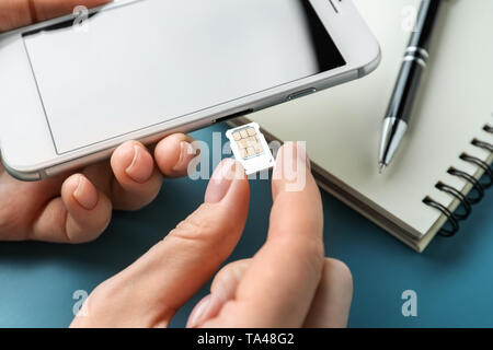 Donna di inserire la scheda SIM nel telefono cellulare, primo piano Foto Stock