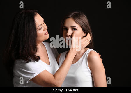 Donna calmare la figlia su sfondo scuro Foto Stock