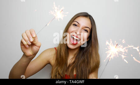 Close-up verticale emotiva di modello femminile azienda botti su sfondo bianco. Ridere ragazza bionda nella parte superiore rossa in posa con luci di bengala. Foto Stock