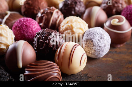 Close up dettaglio di un hotel di lusso a mano il cioccolato bianco palla in una più ampia scelta di specialità cioccolatini o praline su legno rustico Foto Stock