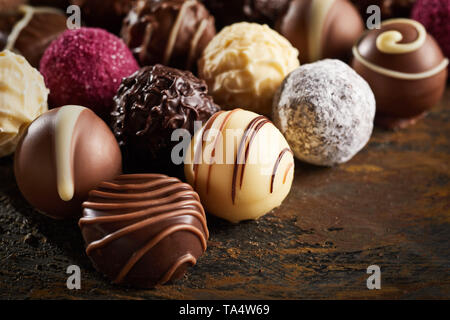 Lusso decorativi fatti a mano bonbon al cioccolato in un display di Praline assortite con messa a fuoco selettiva in vista ravvicinata sul legno rustico Foto Stock