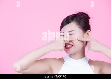 La pelle del viso dei problemi - le donne infelici giovani donne di toccare la sua pelle su un sfondo rosa. Foto Stock