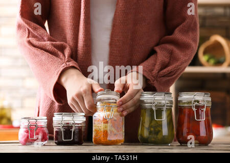 Donna con gustose verdure fermentate in vasi sul tavolo Foto Stock
