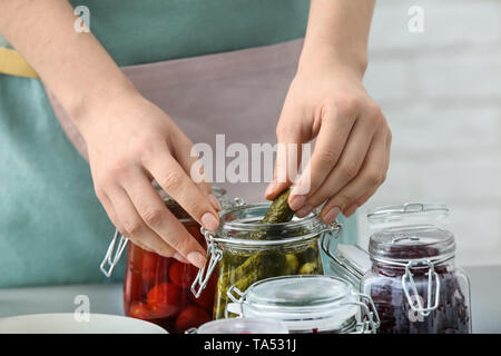 Donna con gustose verdure fermentate in vasi sul tavolo Foto Stock