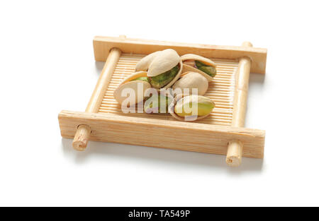 Il bambù piattino con gustosi pistacchi su sfondo bianco Foto Stock