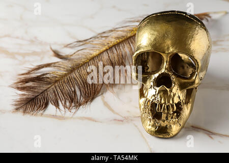 Golden teschio umano con giù su sfondo di marmo Foto Stock