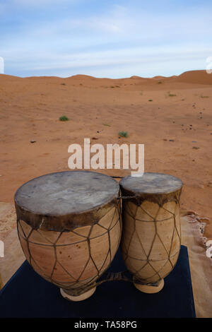 Tradizionali berbere tamburi, strumento musicale, durante il Sunrise in Erg Chebbi dune di sabbia nel deserto del Sahara, Merzouga, Marocco Foto Stock