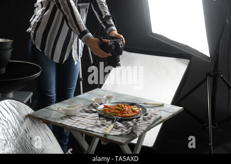 Giovane donna sta immagine di gustosi piatti di pasta in professional photo studio Foto Stock