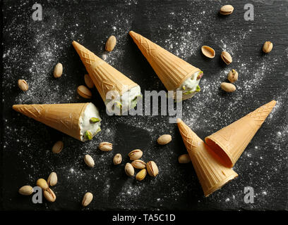 Coni con gustoso gelato al pistacchio su sfondo scuro Foto Stock