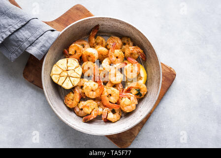 Gamberi arrosto con limone, aglio ed erbe aromatiche. Frutti di mare, shelfish. Gamberi alla griglia con spezie, aglio e limone su pietra bianca di sfondo, copia Foto Stock