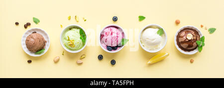 Gelato assortimento. Vari gelati in ciotole su sfondo giallo, banner. Frozen yogurt o gelato biologico - sano dessert estivo. Foto Stock