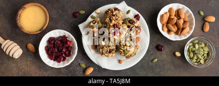 Morsi di energia con noci, semi, mirtilli rossi secchi e miele - vegetariano vegano materie organiche di muesli snack morsi su sfondo scuro, banner. Foto Stock