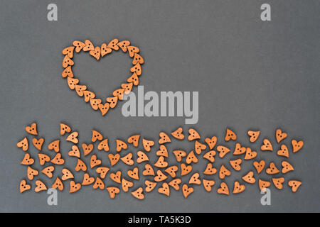 Cuore di pulsanti in legno in forma di cuori su sfondo grigio. Foto Stock