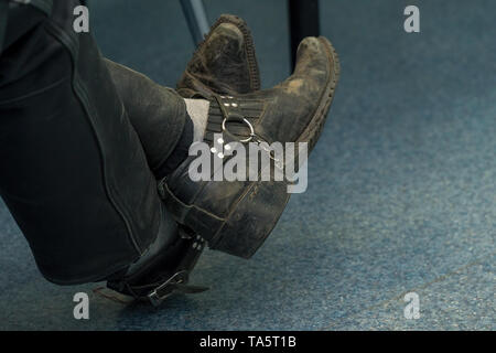 Vecchie scarpe di sporco sulle gambe di uomo seduto Foto Stock