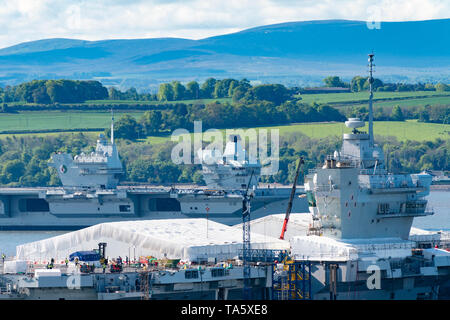 Rosyth, Scotland, Regno Unito. 22 Maggio, 2019. Portaerei HMS Queen Elizabeth ormeggiato a Rosyth nel fiume Forth dopo aver lasciato il bacino di carenaggio ieri dopo una visita a casa sua porta. Lei lascerà il via oggi e tornare al mare in preparazione per Westlant 19 deployment che è progettato per concentrarsi sulle operazioni del suo F-35 degli aerei da caccia. Nella foto; rara vista sia della Royal Navy di portaerei. HMS Queen Elizabeth e in primo piano il sistema HMS Prince of Wales ancora in costruzione nel cantiere di Rosyth. Credito: Iain Masterton/Alamy Live News Foto Stock