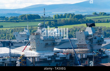 Rosyth, Scotland, Regno Unito. 22 Maggio, 2019. Portaerei HMS Queen Elizabeth ormeggiato a Rosyth nel fiume Forth dopo aver lasciato il bacino di carenaggio ieri dopo una visita a casa sua porta. Lei lascerà il via oggi e tornare al mare in preparazione per Westlant 19 deployment che è progettato per concentrarsi sulle operazioni del suo F-35 degli aerei da caccia. Nella foto; rara vista sia della Royal Navy di portaerei. HMS Queen Elizabeth e in primo piano il sistema HMS Prince of Wales ancora in costruzione nel cantiere di Rosyth. Credito: Iain Masterton/Alamy Live News Foto Stock