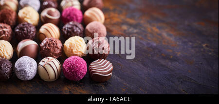 Panorama banner con lusso praline di cioccolato disposti ordinatamente in fila su di legno rustico con copia spazio e dof poco profondo Foto Stock