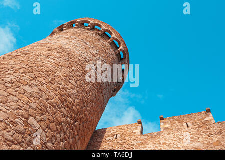 Vista dal basso del vecchio centro medievale torre in pietra e la parete a Tossa de Mar, Spagna Foto Stock