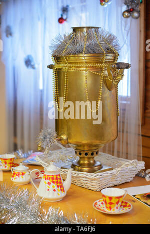 Giallo antico samovar, decorato per il nuovo anno è sul tavolo con utensili per il tè Foto Stock