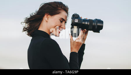 Professional fotografo femmina con fotocamera DSLR a fotografare. Giovane donna con la fotocamera per scattare foto all'aperto. Foto Stock