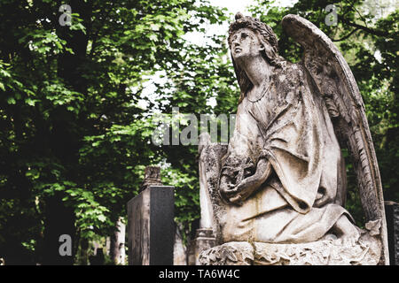 Obsoleta vecchia statura di angelo con croce sulla sulla sepoltura nel cimitero cimitero Lychakiv, Lviv. Foto Stock