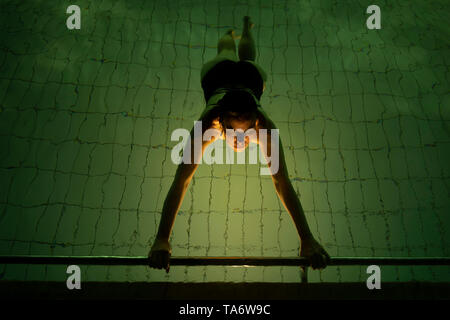 Donna flottante in una accesa Piscina di notte in Svizzera. Foto Stock
