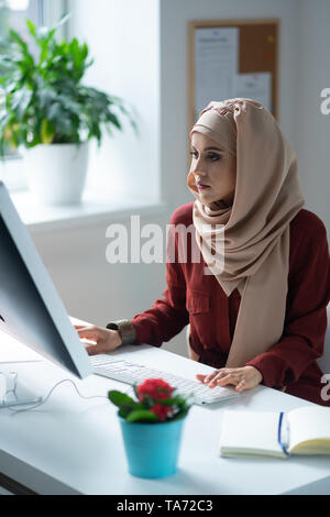 Sentimento donna occupato mentre lavora seduto vicino a un computer Foto Stock