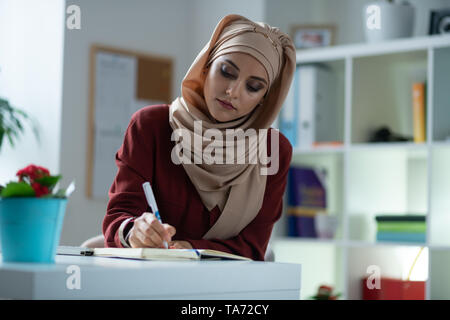 Giovane donna attraente con trucco naturale rendendo alcune note Foto Stock