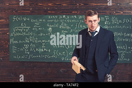 Ansiosi professore guardando sopra i suoi occhiali. Uomo intelligente in tuta azienda prenota in aula. Elite concetto di università Foto Stock