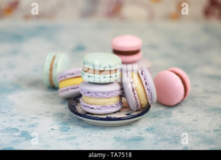 Macaron o amaretto su sfondo blu e colorati di biscotti di mandorle con differente riempimento. Messa a fuoco selettiva Foto Stock