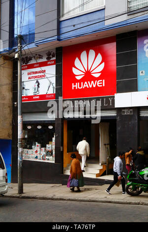 Aymara donna che cammina oltre un segno distributore Huawei, la Paz, Bolivia Foto Stock