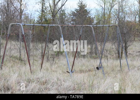 Invecchiamento set swing in natura una zona con erba alta crescente intorno ad esso Foto Stock