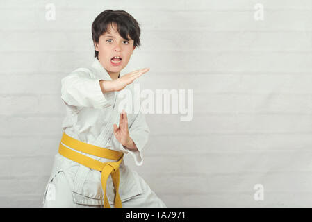 Bambino in posizione di karate contro Sfondo mattone Foto Stock