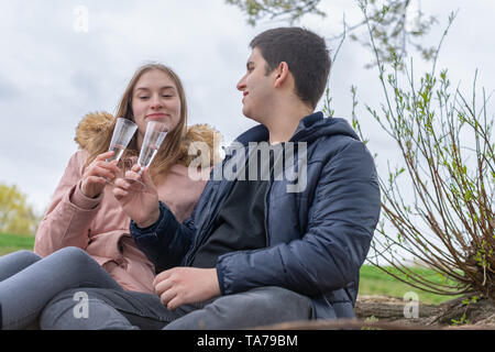 Un giovane in amore sit in natura e toast con bicchieri di champagne Foto Stock