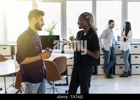 Diversi amici due colleghi in piedi presso l'ufficio distratti dal lavoro bere il caffè di conversazione informale. Capo Pianificazione dipendente nuovo progetto discutere in Foto Stock