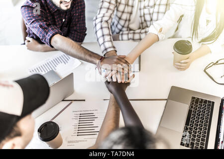 Team hanno messo le mani insieme, mostrano il collegamento e di alleanza, vista dall'alto del tavolo di lavoro. Teambuilding in ufficio, giovani uomini e donne d'affari in casuale unite Foto Stock