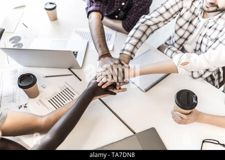Team hanno messo le mani insieme, mostrano il collegamento e di alleanza, vista dall'alto del tavolo di lavoro. Teambuilding in ufficio, giovani uomini e donne d'affari in casuale unite Foto Stock