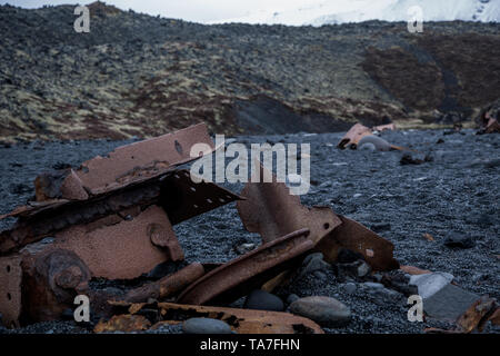 Rusty detriti sulla spiaggia nera di Islanda Foto Stock