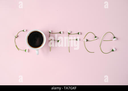 "Caffè' fatto di fiori di camomilla e la tazza di caffè su sfondo rosa. Concetto creativo. Appartamento laico, vista dall'alto, spazio di copia Foto Stock
